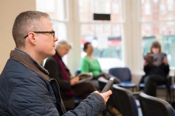 Man sat in a chair in a health centre waiting room